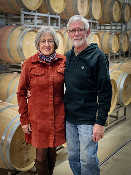 Larry & Marilyn Kennel in front of wine barrels