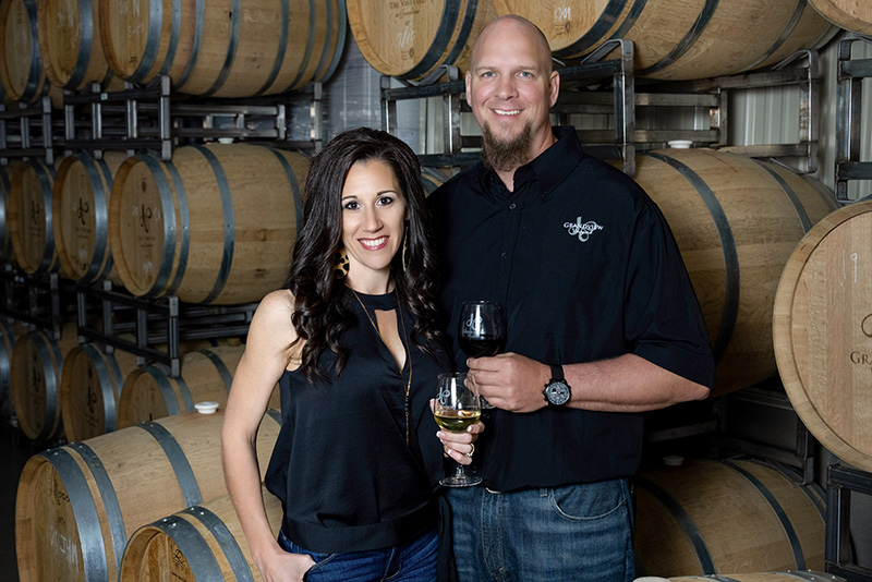 Sarah & Scott Haines in front of wine barrels