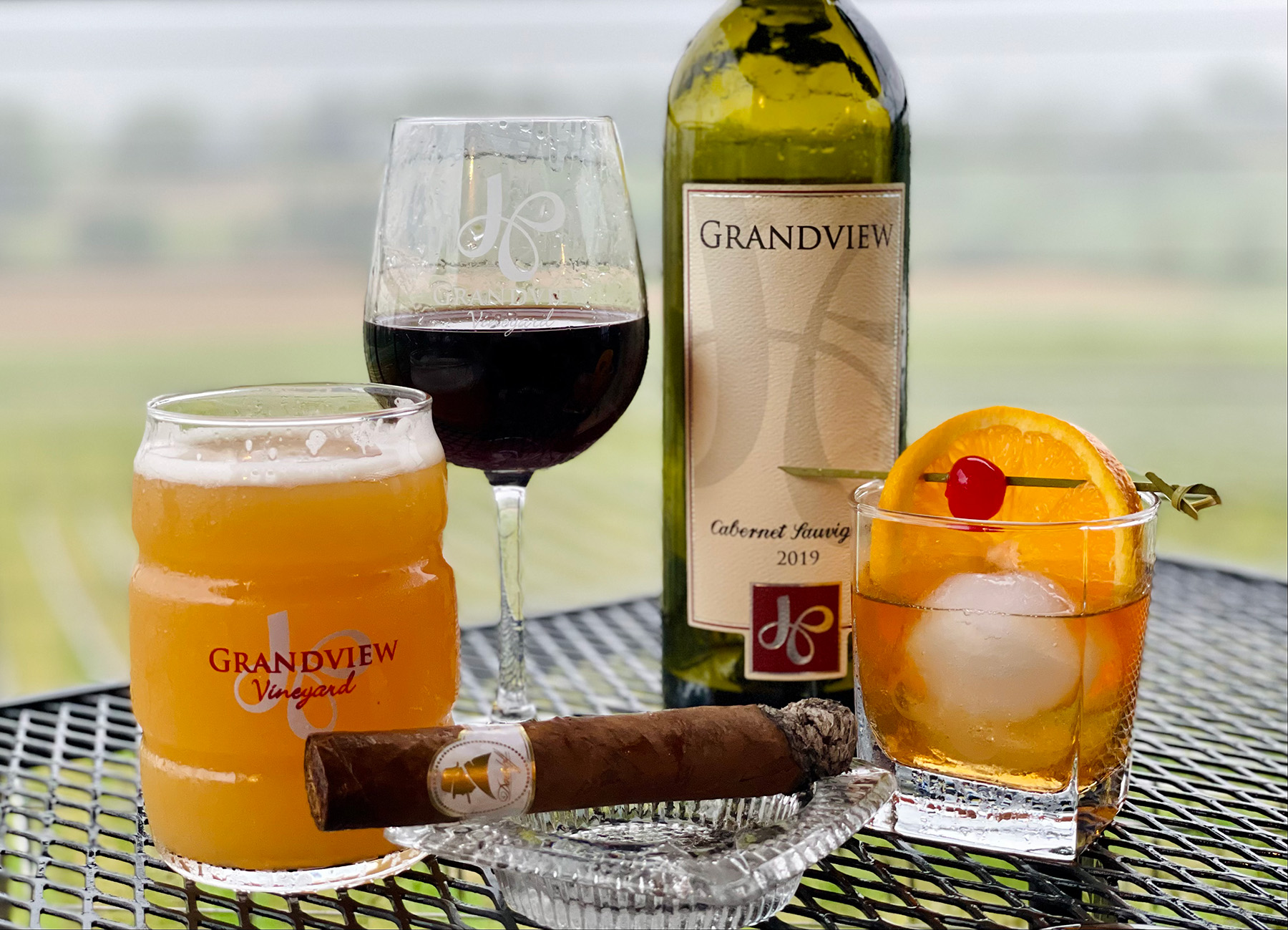 Cigar and GrandView Wine displayed on table overlooking vineyards